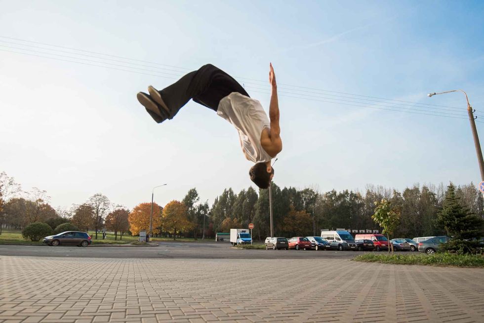 A teenager doing a backflip on open ground