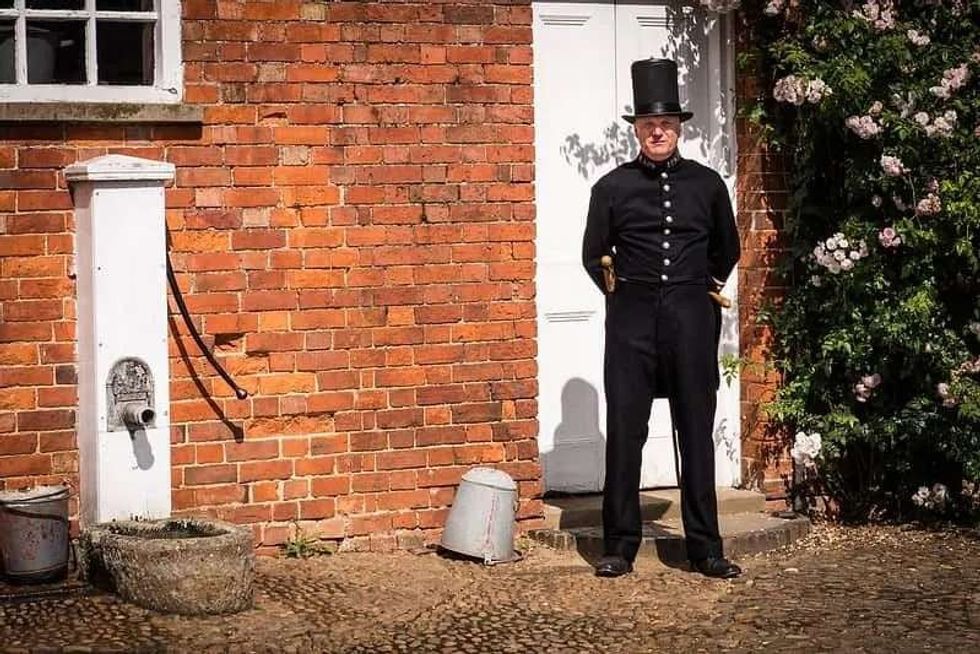 A Victorian policeman standing outside a house in his uniform.