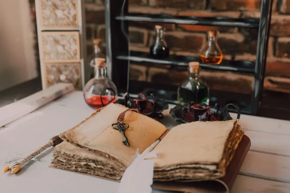 A wizard notebook with feather pen, key and magic potion bottles