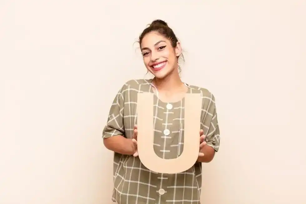 A woman holding wooden letter U