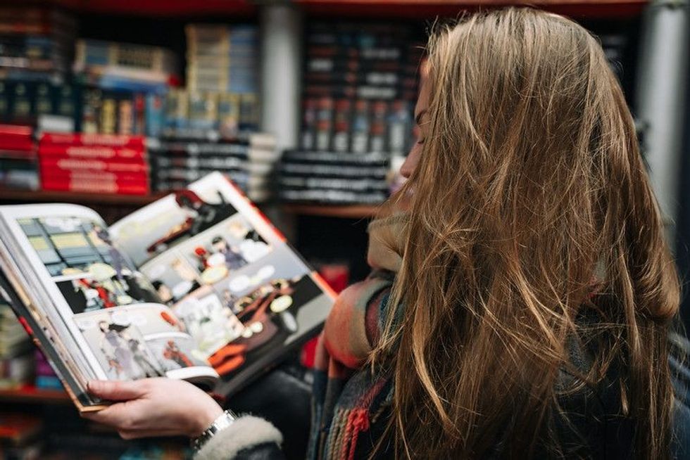 A woman in a bookstore holding an open comic book in the ruffs
