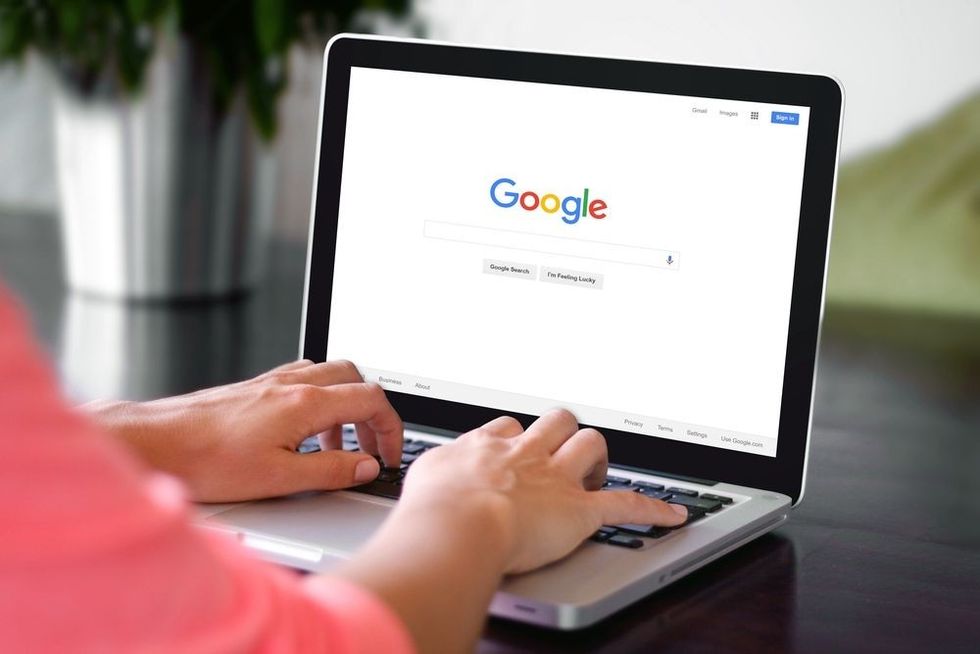 A woman is typing on Google search engine from a laptop.