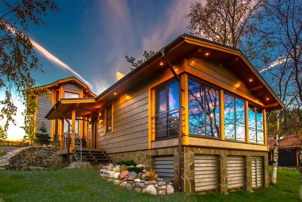 A wooden cottage with a green lawn.