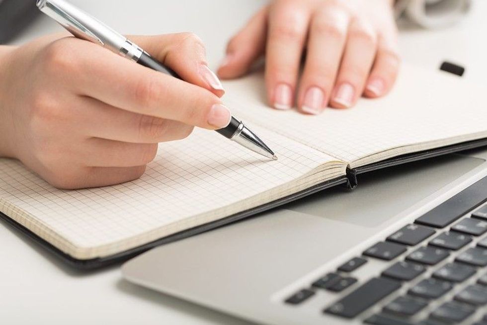 A writer writing in book with his pen.