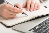 A writer writing in book with his pen.
