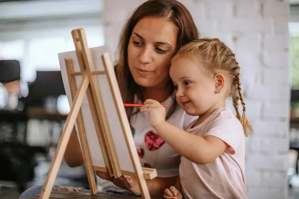 A young girl taking part in an art event and showing off her painting skills.