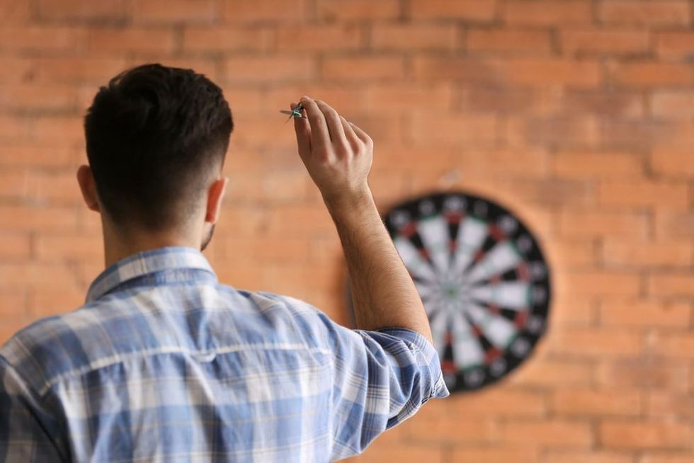A young man playing darts