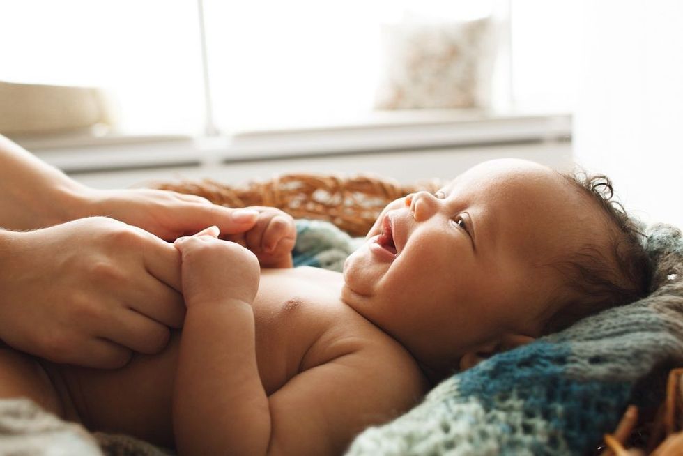 Adorable newborn child looking up at mother smiling 