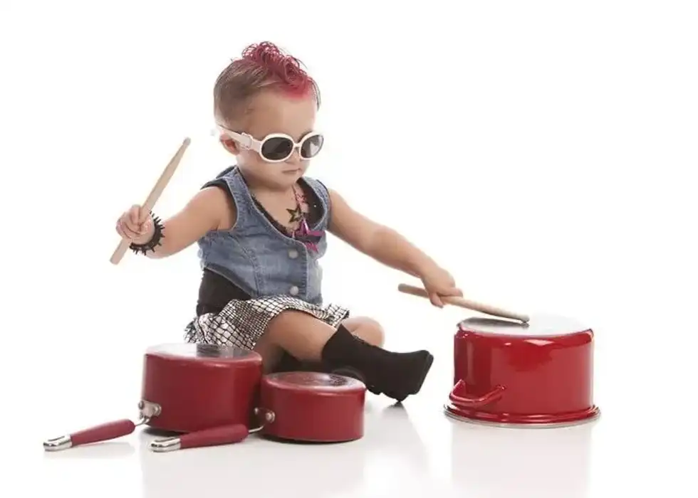 Adorable toddler with a pink mohawk and banging on pots and pans.