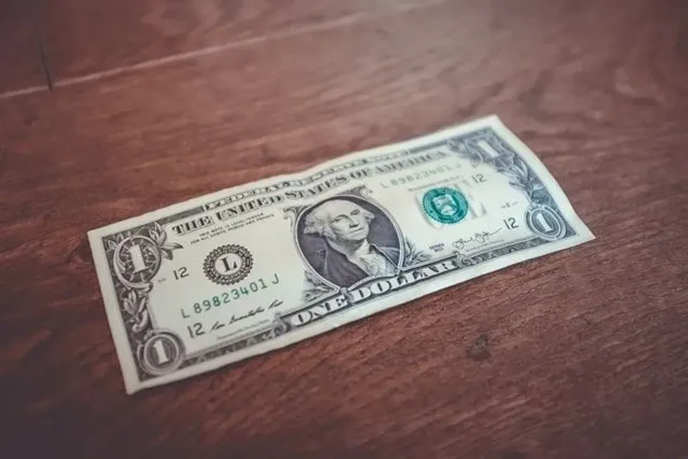 An image of a 1 US Dollar bill on brown wooden surface