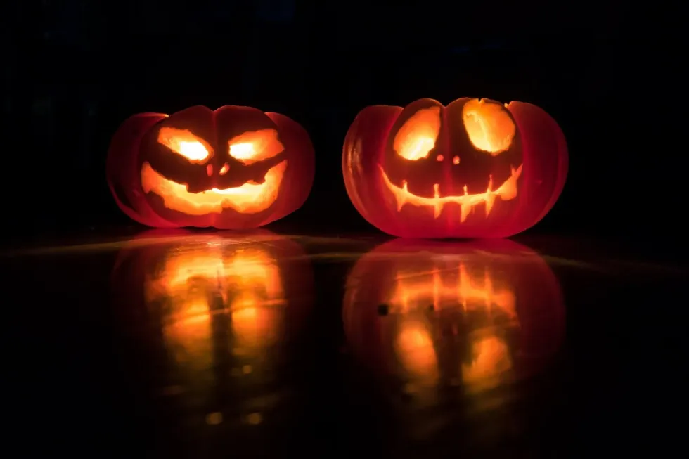 An image of two Halloween pumpkins on a black background with glowing eyes and mouth making it look deathly