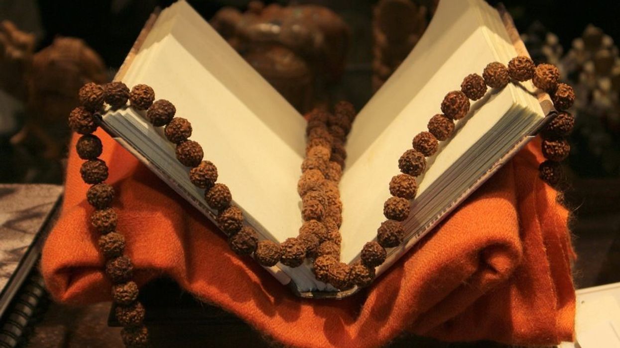 An old book on a red cloth with Rudraksha beads