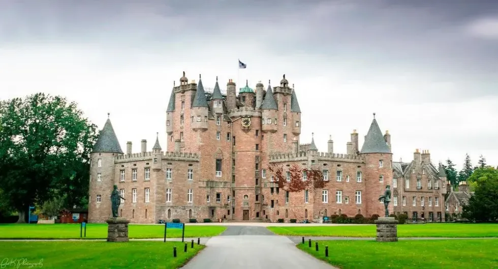 An outside view of Glamis Castle and the green grass of the grounds surrounding it.