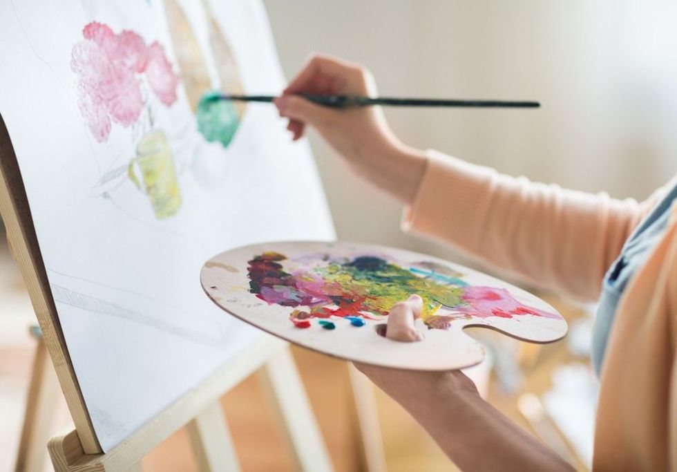 art, creativity and people concept - close up of artist with palette and brush painting still life on paper at studio