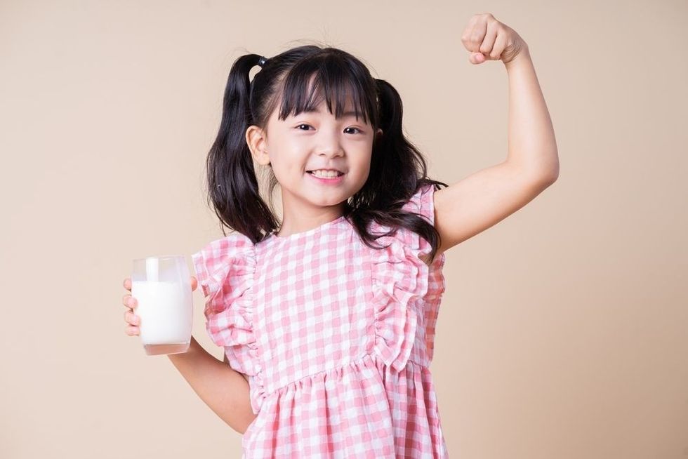 Asian girl wearing pink top holding cup of milk