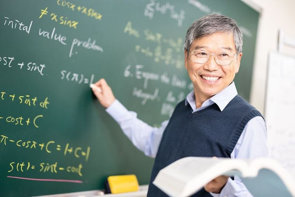 Asian senior male calculus professor writing.