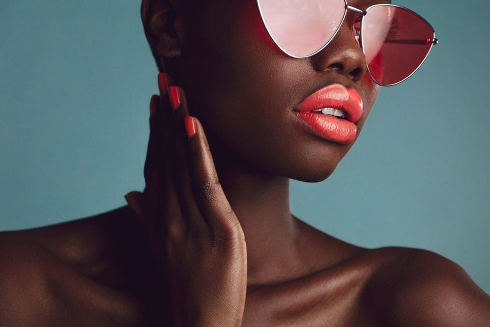 Attractive woman with red lipstick and nailpaint looking away on grey background.