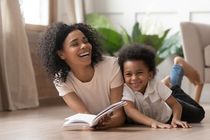 Aunt and her nephew laughing and reading book in the house