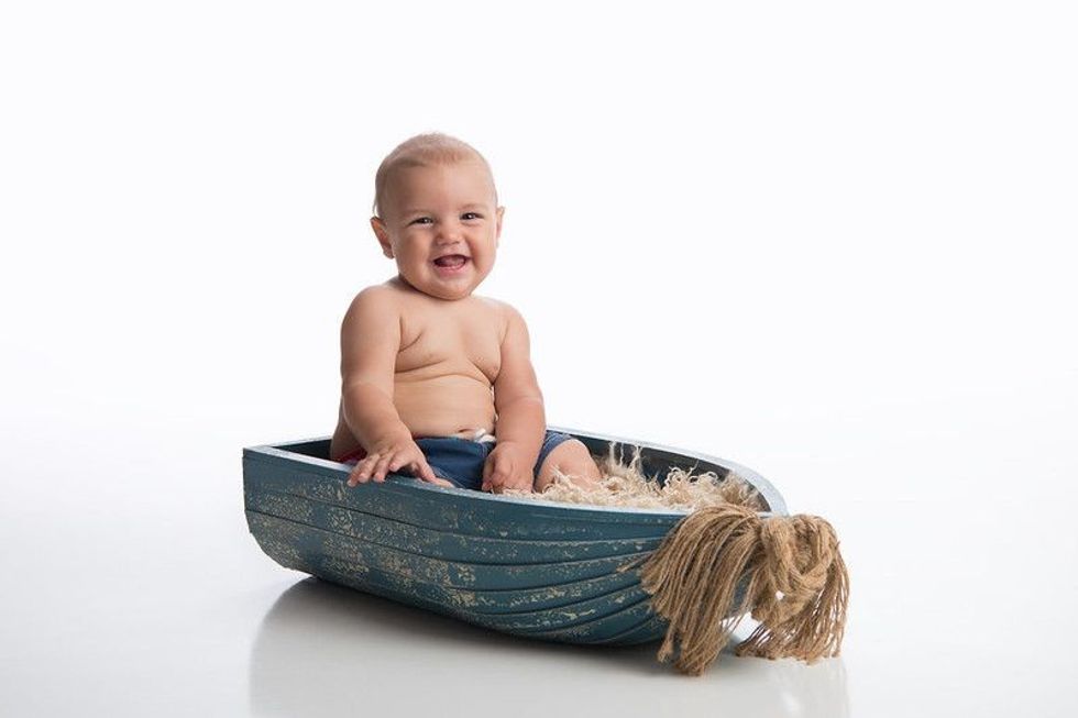Baby boy sitting in a rustic boat