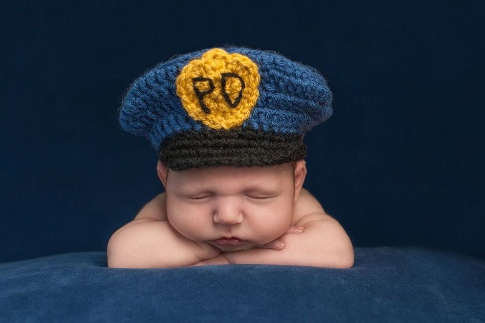 Baby boy wearing a blue crocheted police officer hat