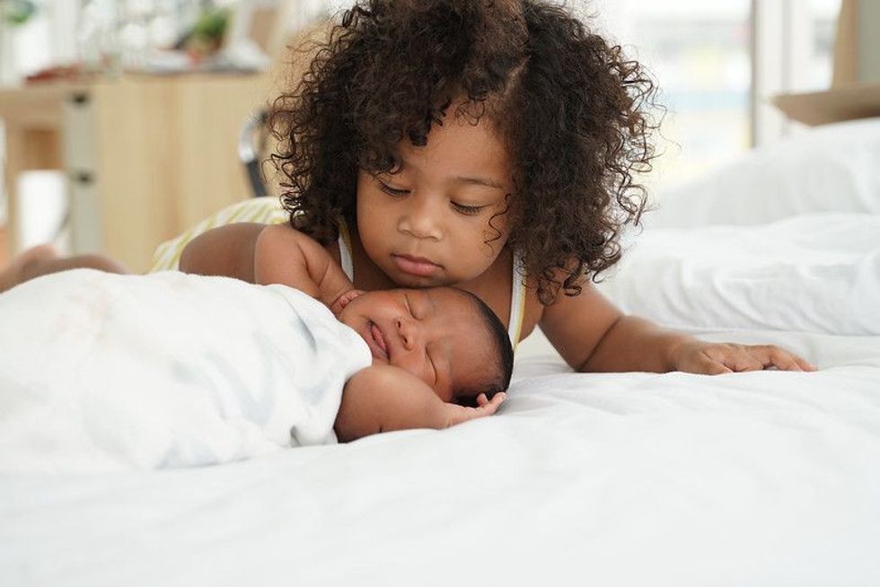 Baby girl adoring her newborn sibling