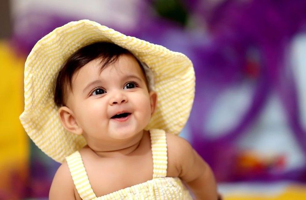 Baby girl wearing yellow hat and dress