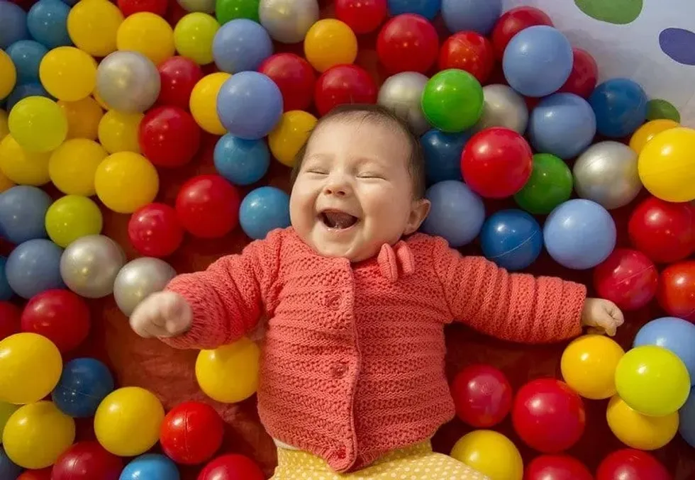 Baby laughing in a sensory ball pit min