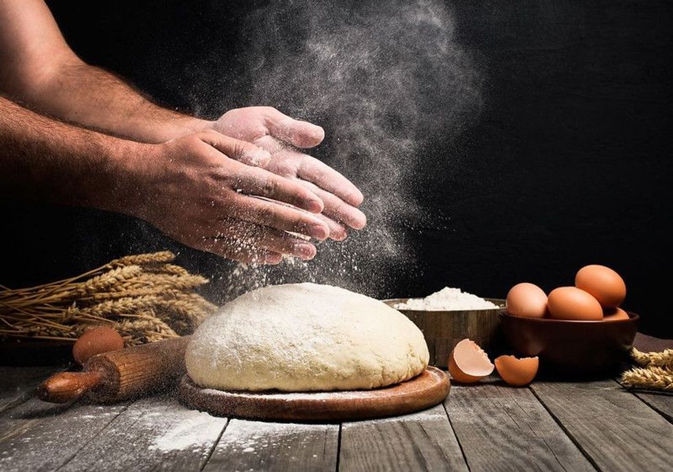 Baker dusting dough with flour