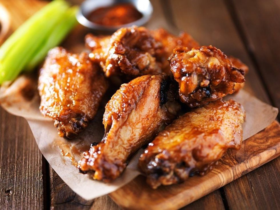 Barbecue chicken wings close up on wooden tray shot.