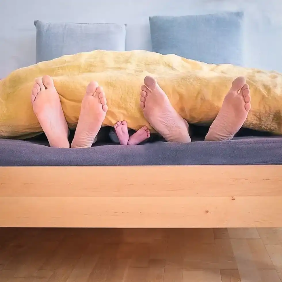 Bare feet sticking out of the bed covers.