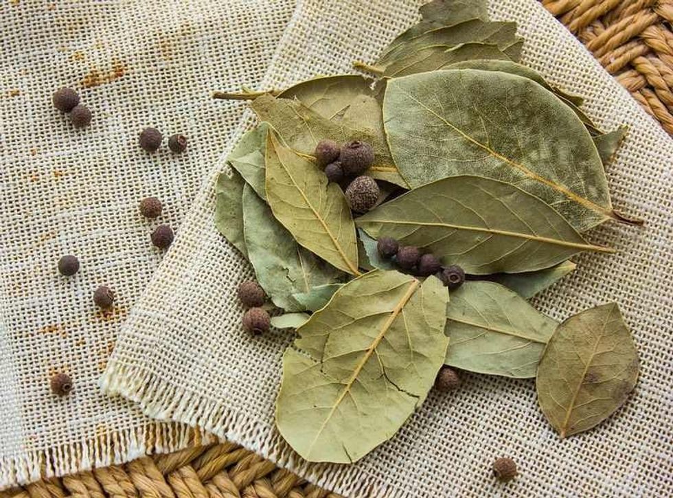 Bay leaves on a straw background with pepper.