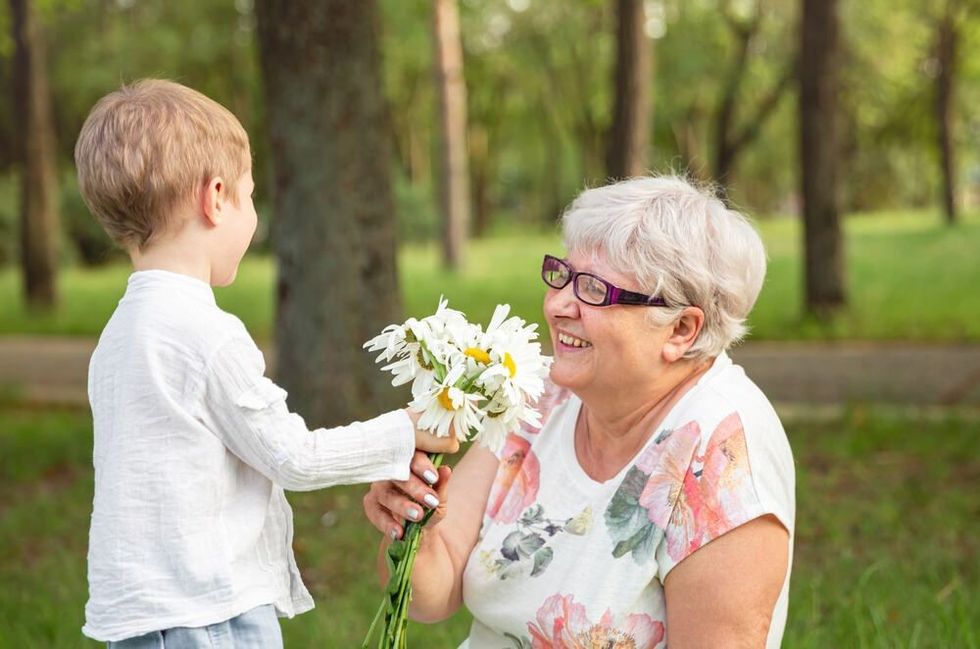 Beautiful boy giving a flower to grandma