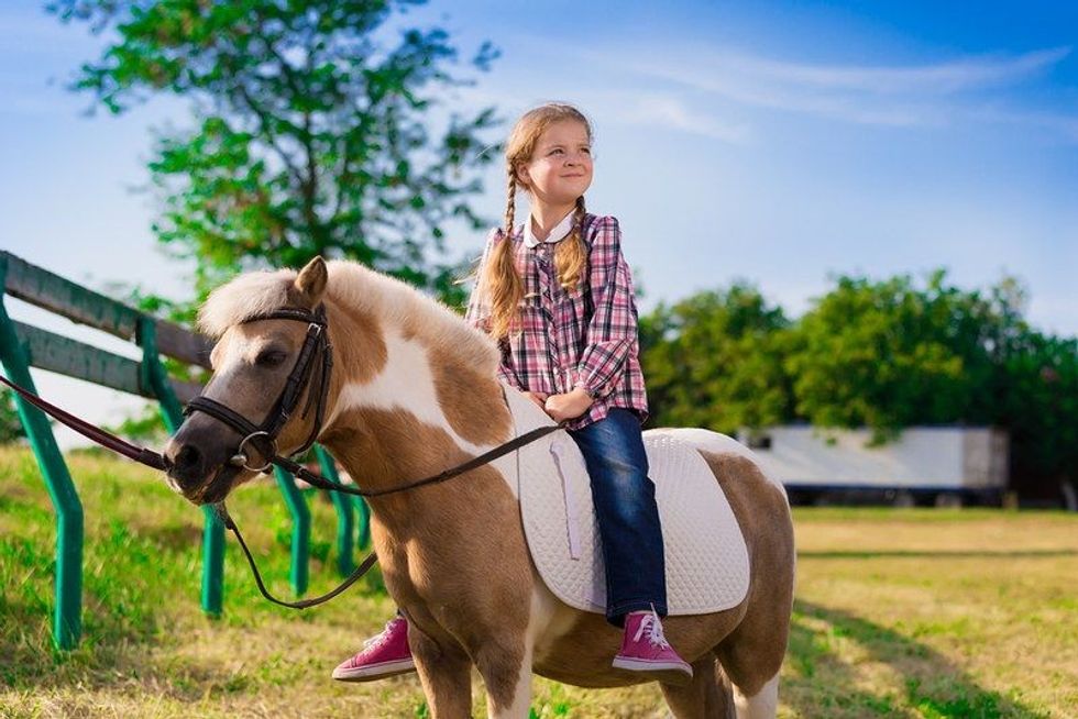 Beautiful little cowgirl riding horse pony