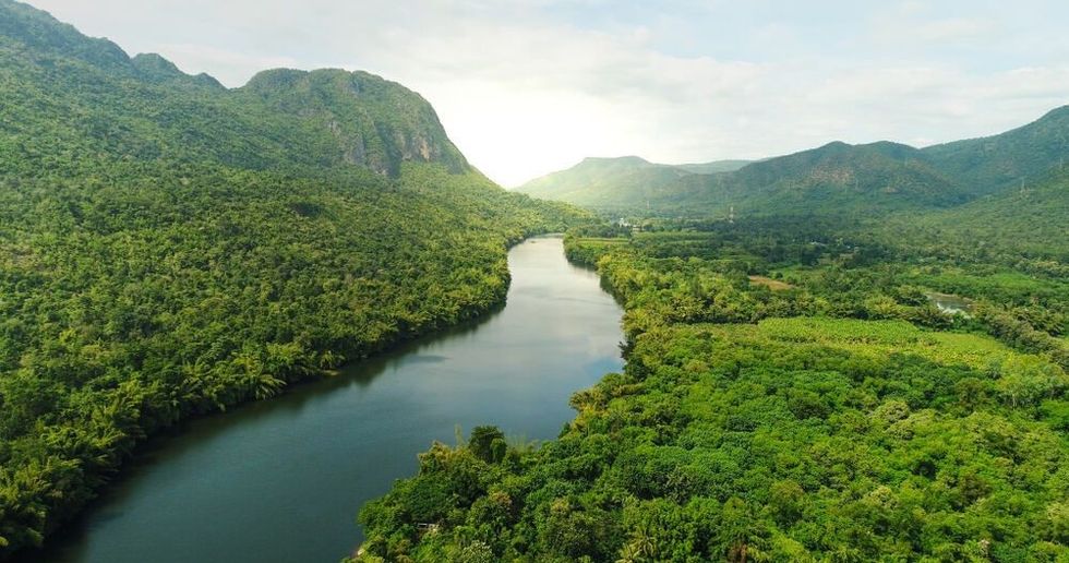 Beautiful natural scenery of river in southeast Asia tropical green forest with mountains in background