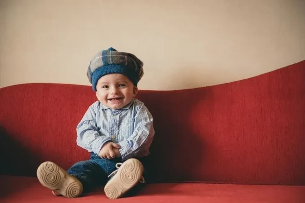 Beautiful Scottish baby boy sitting on a red couch