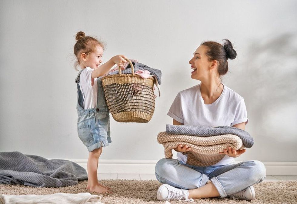 Beautiful young woman and girl doing laundry at home.