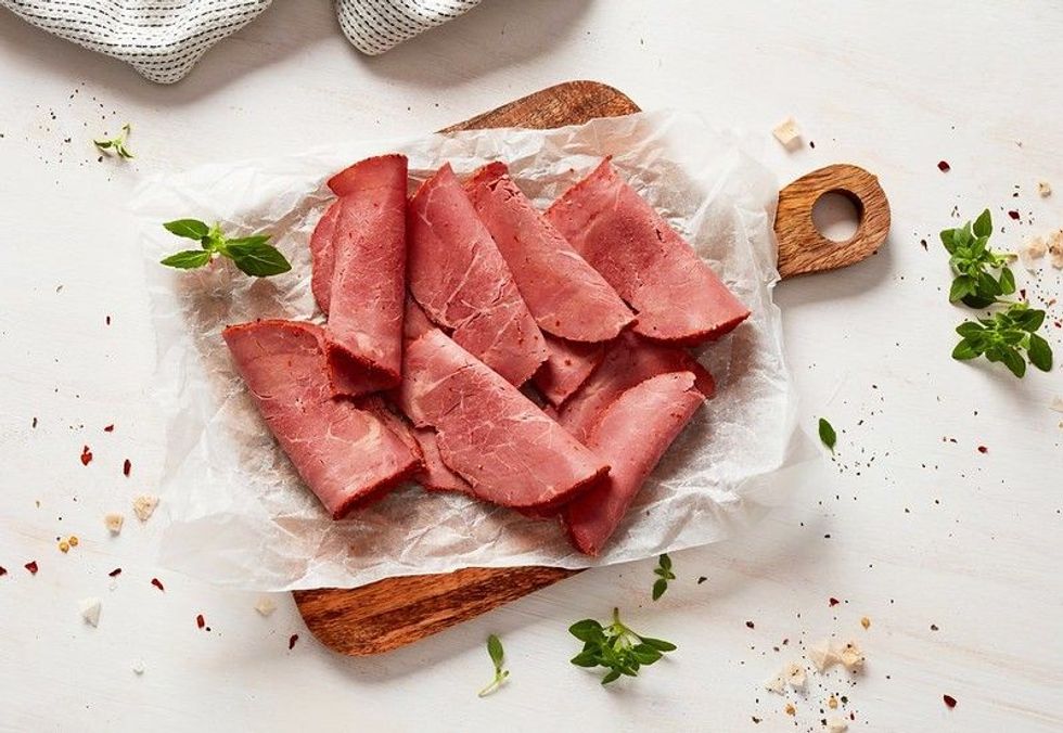 Beef pastrami slices on cutting board.