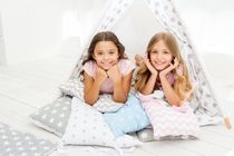 Best friends spend time together lay in tipi house at their sleep over.