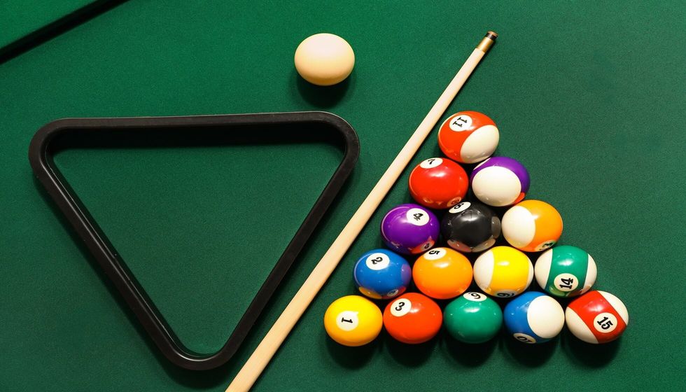 Billiard or Pool balls with cue and rack on green table.