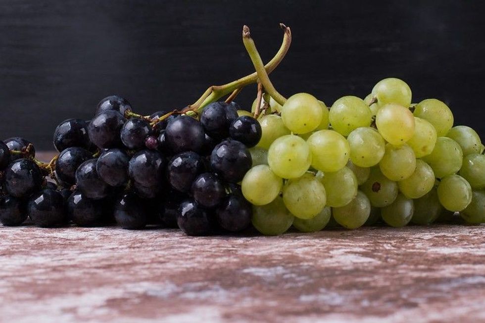 Black and green grapes on wooden table