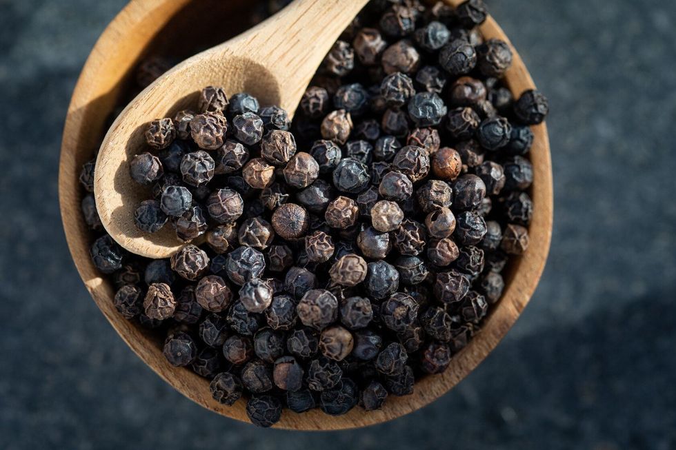Black peppercorns in a wooden bowl