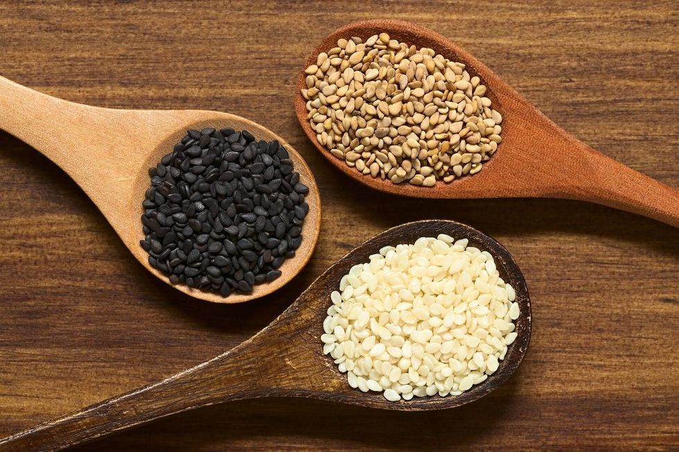 Black white and roasted sesame seeds on small wooden spoons