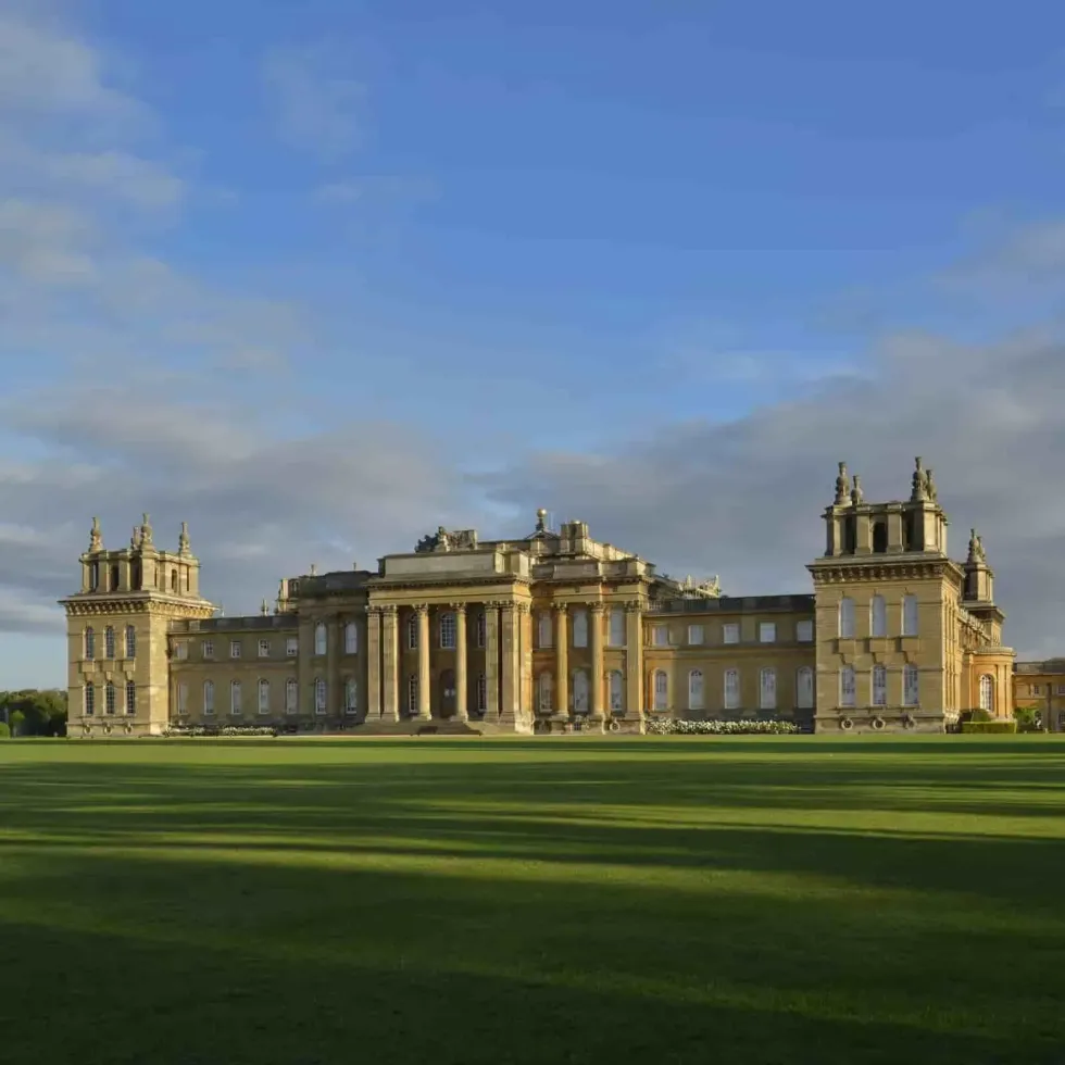 Blenheim Palace exterior against the blue sky, showing lush green acres in front.