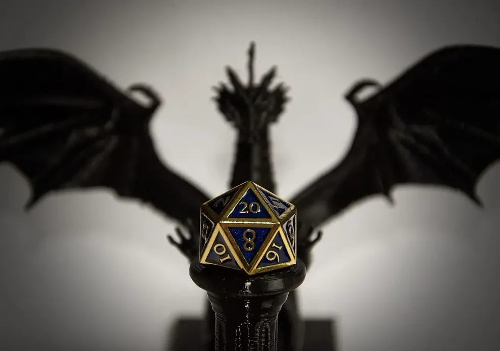 Blue d20 dice with golden lining in front of black dragon