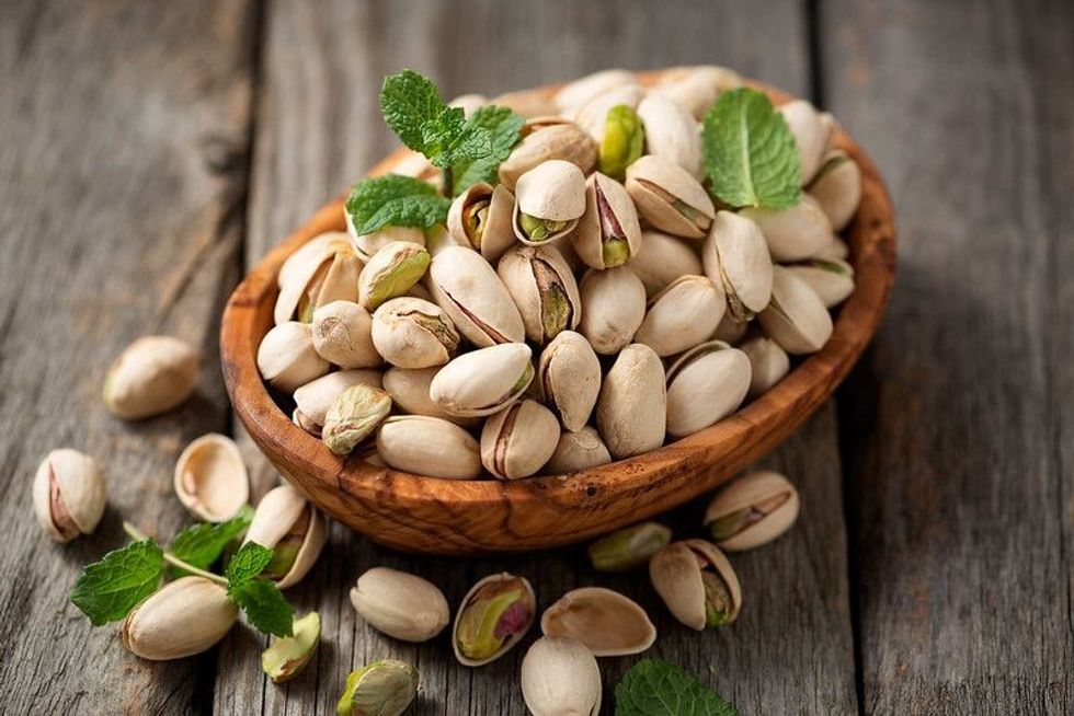 Bowl with pistachios on a wooden table.