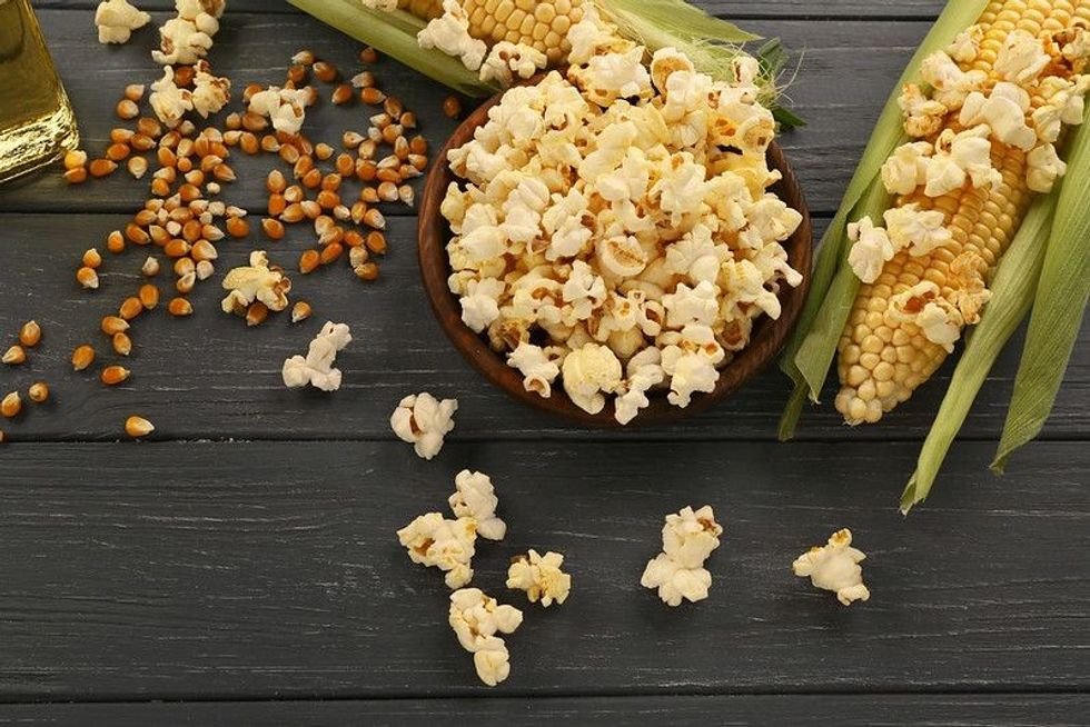 Bowl with tasty traditional popcorn and corncobs.
