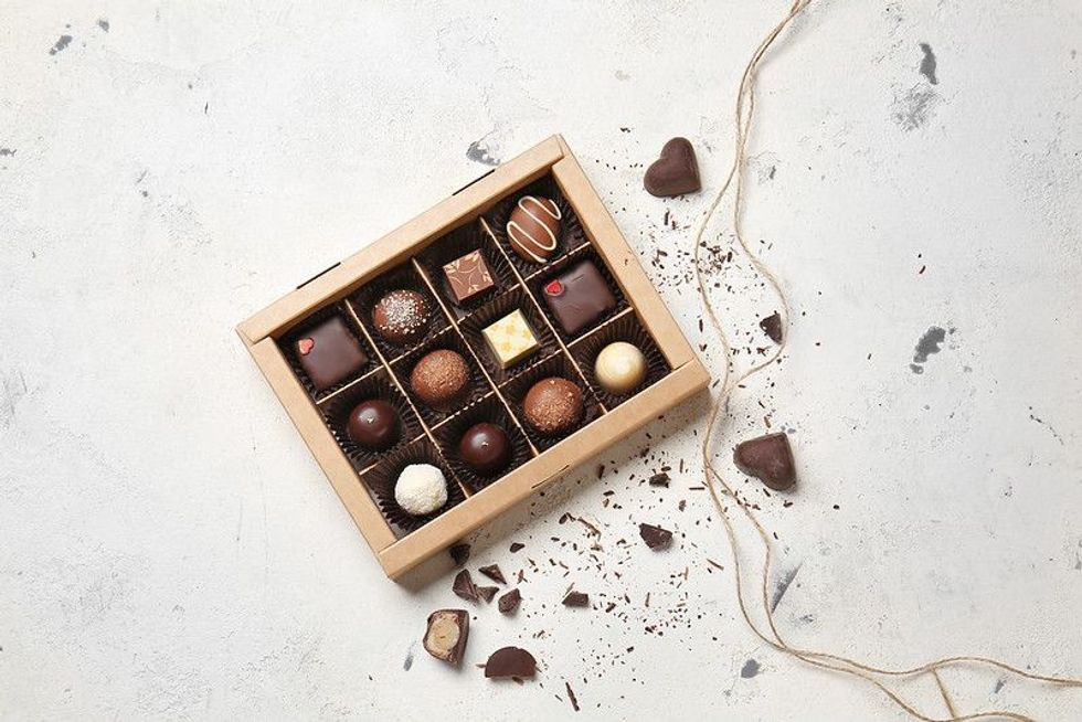 Box with delicious chocolate candies on light background.