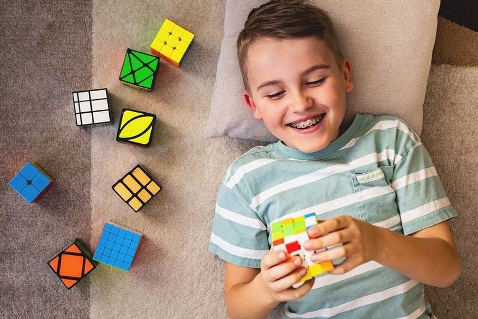 Boy assembling multicolored Rubiks cube.
