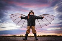 Boy with wings at sunset imagines himself a pilot and dreams of flying