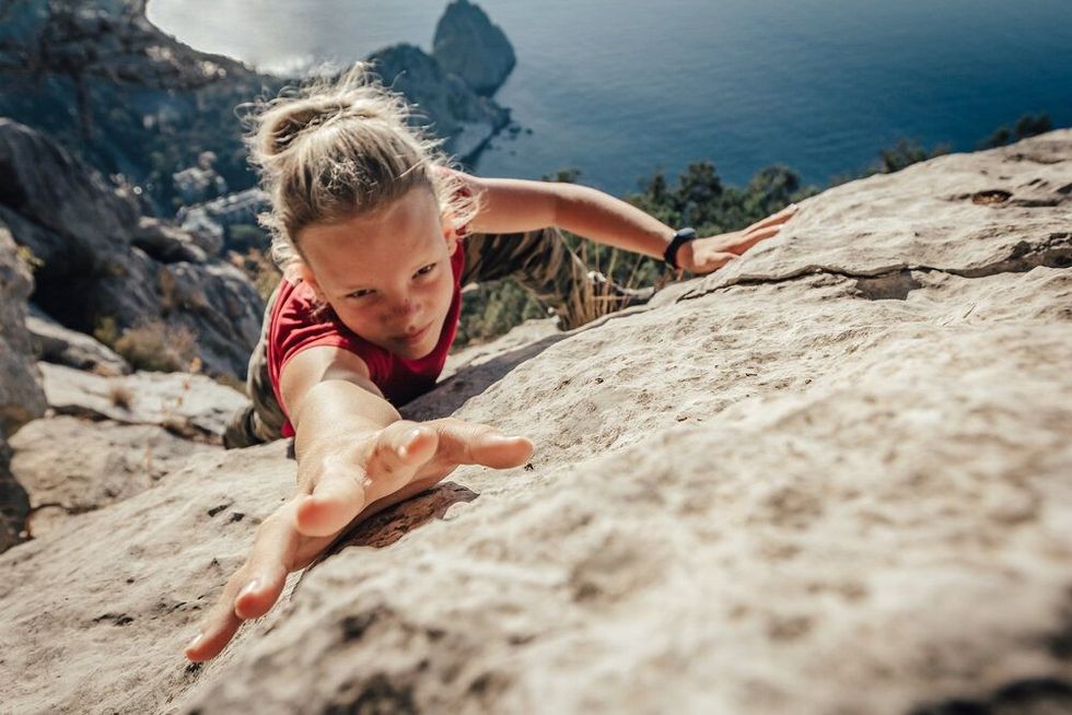 Brave young woman climber fearlessly climbs up a mountain